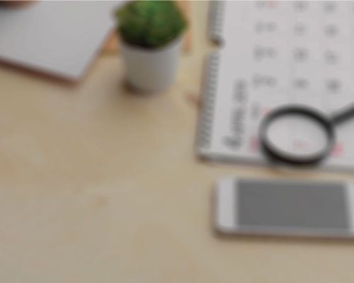 Blurred Image of a Cactus, Calendar, Magnifying Glass, and Phone